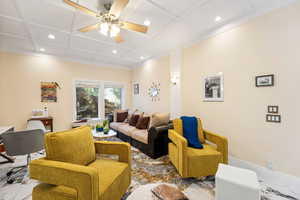 Living room featuring recessed lighting, ceiling fan, coffered ceiling, and marble finish flooring