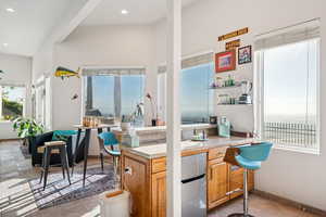 Kitchen with tile counters, a peninsula, stainless steel fridge, recessed lighting, and light tile patterned floors