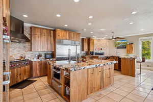 Kitchen with light stone countertops, stainless steel appliances, ceiling fan, light tile patterned flooring, and recessed lighting