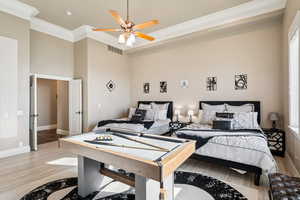 Bedroom with light wood-style flooring, crown molding, a ceiling fan, and a high ceiling