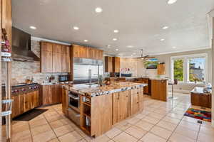 Kitchen featuring light stone counters, stainless steel appliances, wood finish cabinets, recessed lighting, and open shelves