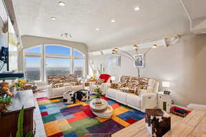 Living room featuring wood finished floors, vaulted ceiling, and recessed lighting
