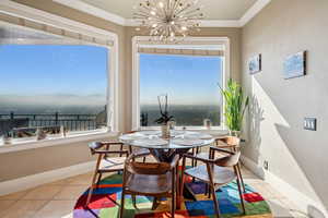 Dining room with suspended lighting, light tile patterned floors, ornamental molding, and a water view