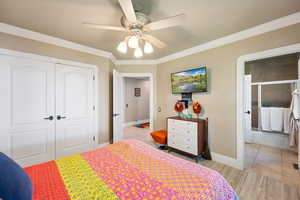 Bedroom featuring ornamental molding, a closet, light wood-type flooring, and ceiling fan