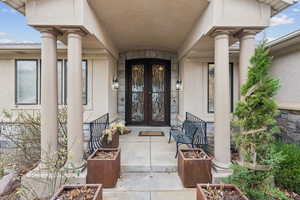 Doorway to property with a porch, french doors, stucco siding, and stone siding