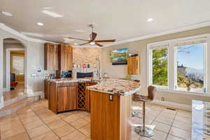 Kitchen with wood finish cabinetry, light stone counters, a peninsula, arched walkways, and a fireplace