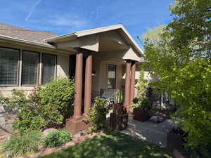 View of exterior entry featuring stucco siding and a lawn