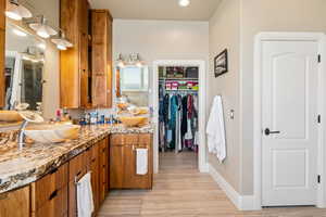 Full bath featuring double vanity, a spacious closet, light wood-type flooring, and recessed lighting
