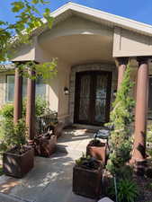 Doorway to property featuring stone siding, stucco siding, and french doors