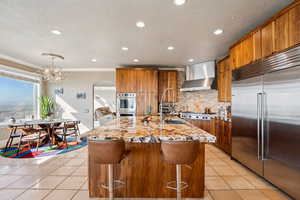 Kitchen with wood finish cabinets, stainless steel appliances, arched walkways, light stone countertops, and light tile patterned flooring