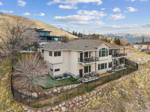 Back of property with a fenced backyard, stucco siding, a mountain view, and a balcony