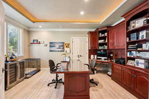 Office featuring wine cooler, light wood-type flooring, recessed lighting, built in study area, and a raised ceiling