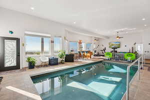 Indoor pool featuring a ceiling fan and a sunroom
