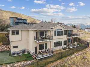 Rear view of house featuring a balcony, a fenced backyard, a mountain view, and a patio