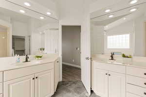 Full bath featuring two vanities, recessed lighting, and vaulted ceiling