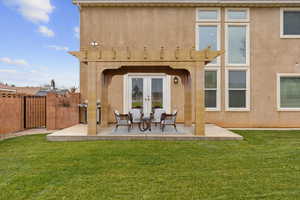 Rear view of property with a patio area, a gate, stucco siding, and a yard