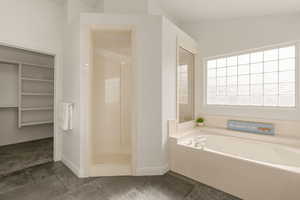 Bathroom with a stall shower, a walk in closet, and a garden tub