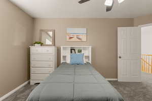 Bedroom with dark colored carpet, a ceiling fan, and a textured ceiling