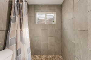 Full bath featuring tiled shower and toilet