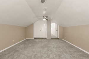 Additional living space with a textured ceiling, light colored carpet, and ceiling fan