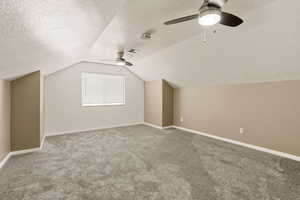 Additional living space featuring ceiling fan, carpet, and a textured ceiling