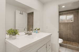 Bathroom featuring vanity, tiled shower, and light tile patterned floors