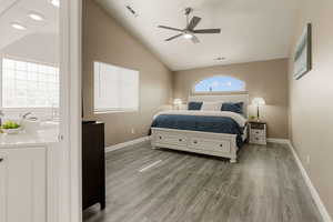 Bedroom featuring wood finished floors, lofted ceiling, a ceiling fan, and connected bathroom