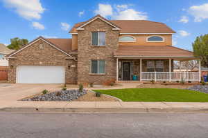 View of front of house with covered porch, a tile roof, and brick siding