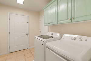 Laundry room featuring light tile patterned flooring, cabinet space, and washing machine and clothes dryer
