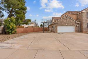 View of side of property with concrete driveway, an attached garage, a tiled roof, and brick siding