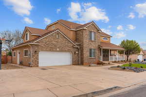 Traditional-style home with driveway, covered porch, brick siding, an attached garage, and a tiled roof