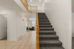 Stairway featuring a high ceiling and tile patterned flooring