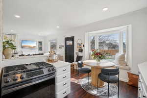 Kitchen featuring stainless steel range with gas stovetop, dark wood finished floors, crown molding, recessed lighting, and white cabinets