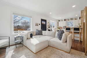 Living room with hardwood / wood-style floors, healthy amount of natural light, recessed lighting, and crown molding