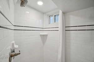 Full bath with a textured ceiling and tiled shower