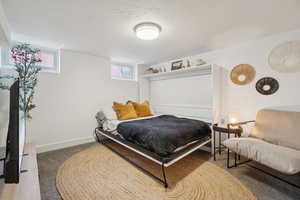 Carpeted bedroom with a textured ceiling and baseboards
