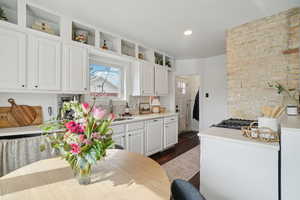Kitchen with white cabinets, light countertops, backsplash, and dark wood-type flooring
