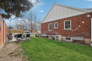 Back of house featuring board and batten siding, a patio, and brick siding