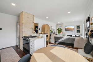 Bedroom with dark wood-style flooring, recessed lighting, freestanding refrigerator, a fireplace, and ornamental molding