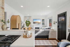 Living room with crown molding, recessed lighting, a fireplace, healthy amount of natural light, and wood finished floors