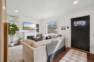 Living room with wood finished floors, a fireplace, plenty of natural light, recessed lighting, and ornamental molding