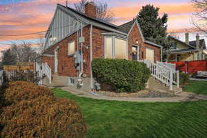 Property exterior at dusk with brick siding, a chimney, and entry steps