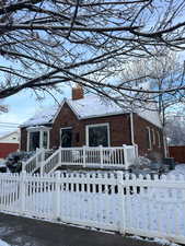 View of front facade with brick siding, a chimney, a fenced front yard, and a gate