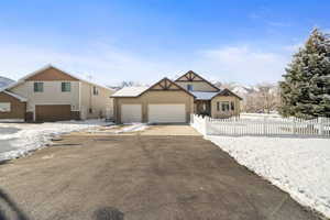 View of front of property featuring a fenced front yard, concrete driveway, a mountain view, and a garage