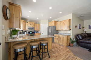 Kitchen with a peninsula, light wood finish cabinetry, a breakfast bar area, light wood-type flooring, and stainless steel appliances