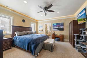 Bedroom with carpet floors, a ceiling fan, crown molding, ensuite bath, and recessed lighting