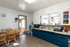 Kitchen featuring light wood-type flooring, dual tone cabinets, glass fronted cabinets, stainless steel microwave, and tasteful backsplash