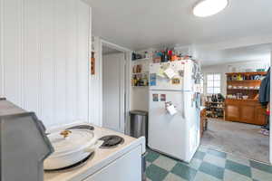 Cottage kitchen featuring tile patterned floors, white appliances, and white cabinets