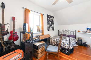 Cottage bedroom featuring ceiling fan, vaulted ceiling, and wood finished floors