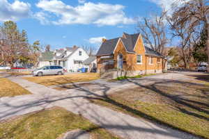 View of front of house featuring brick siding, a chimney, a residential view, and a front lawn